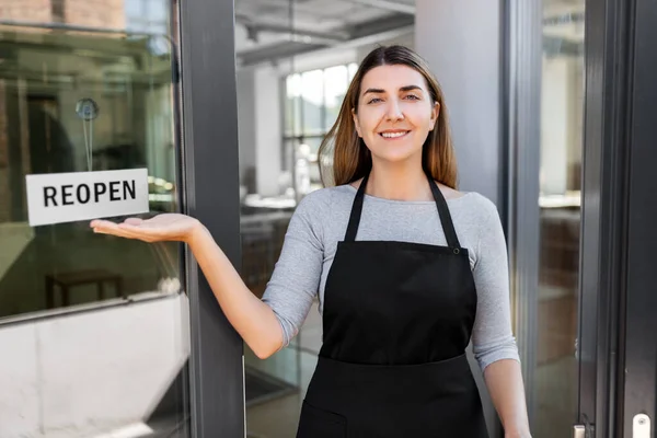 Femme heureuse montrant bannière de réouverture sur le verre de porte — Photo