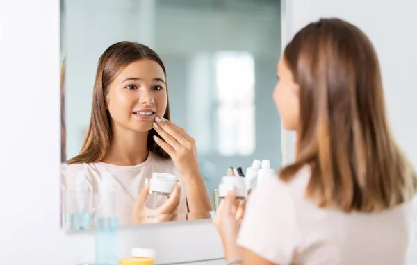 Teenager-Mädchen mit Feuchtigkeitscreme im Badezimmer — Stockfoto