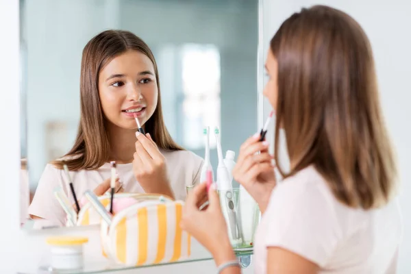 Chica adolescente aplicando brillo de labios en el baño — Foto de Stock