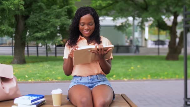 Estudiante africana feliz lectura libro en la ciudad — Vídeo de stock