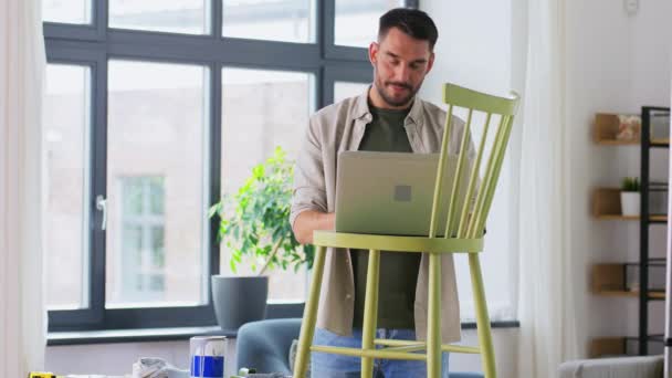 Mand med laptop forbereder gamle stol til renovering – Stock-video