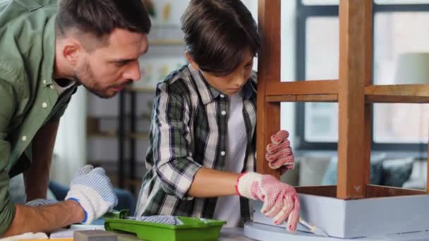 Baba ve oğul eski masayı gri renge boyuyorlar. — Stok video