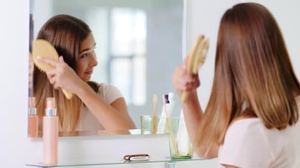 Nastolatka dziewczyna szczotkowanie włosy z grzebieniem w łazience — Wideo stockowe