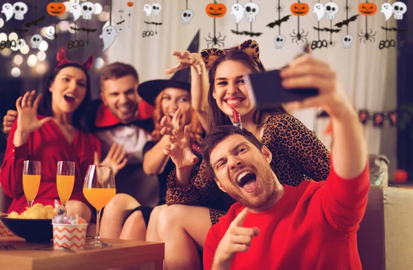 Счастливые друзья в костюмах на Хэллоуин делают селфи — стоковое фото
