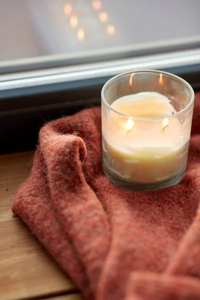 Maglione di lana e candela bruciano sul davanzale della finestra — Foto Stock