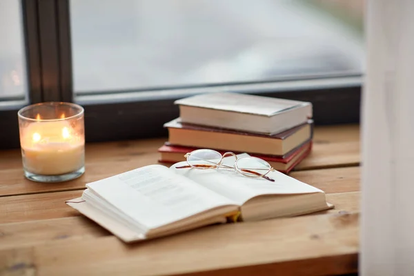 Книги, стаканы и горящие свечи на подоконнике — стоковое фото
