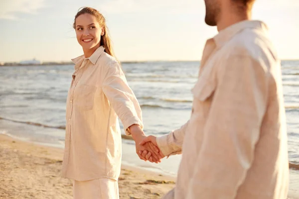 Ευτυχισμένο ζευγάρι κρατώντας τα χέρια στην καλοκαιρινή παραλία — Φωτογραφία Αρχείου