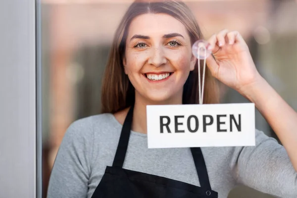 Femme heureuse accrochant bannière rouverte au verre de porte — Photo