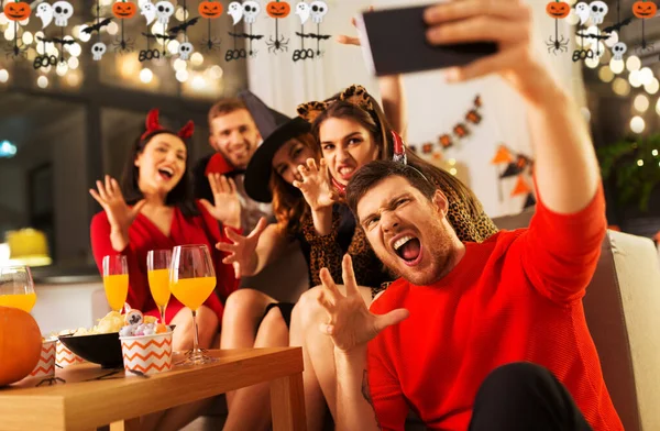 Glada vänner i halloween kostymer tar selfie — Stockfoto