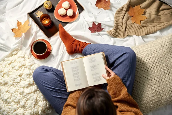Молодая женщина читает книгу дома осенью — стоковое фото