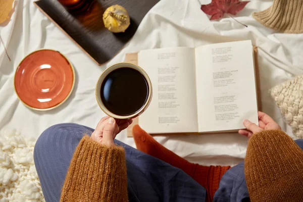 Kvinne som drikker kaffe og leser bok om høsten – stockfoto