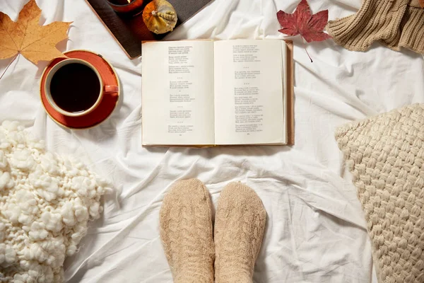 Book, cup of coffee and autumn leaves in bed — Stock Photo, Image