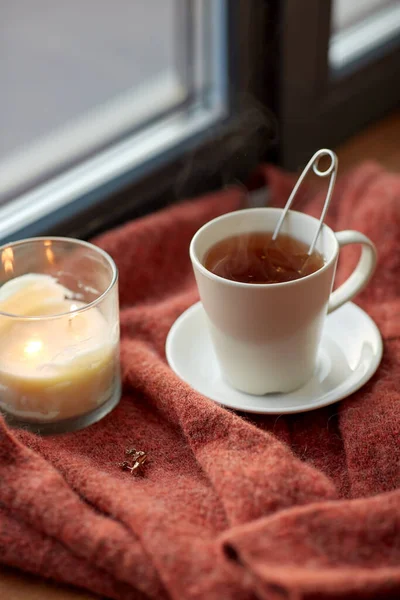 Taza de té y vela en el alféizar de la ventana — Foto de Stock