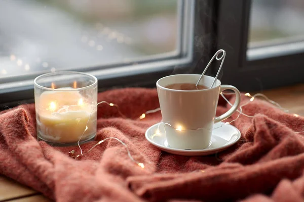 Tasse de thé et bougie sur le rebord de la fenêtre — Photo