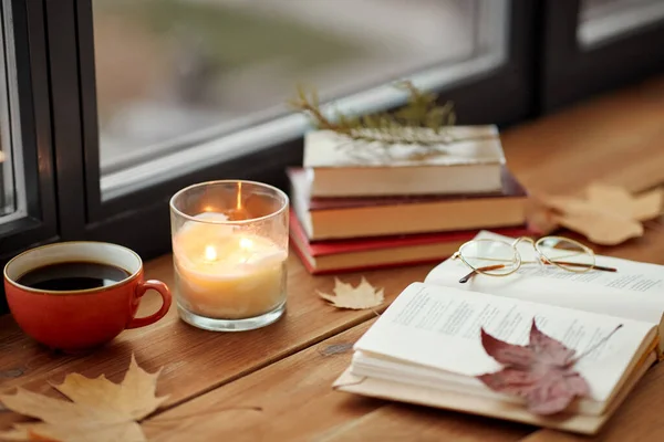 Bok, kaffe och ljus på fönsterbräda på hösten — Stockfoto