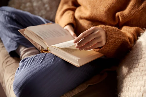 Kvinna i varm tröja läsa bok hemma — Stockfoto