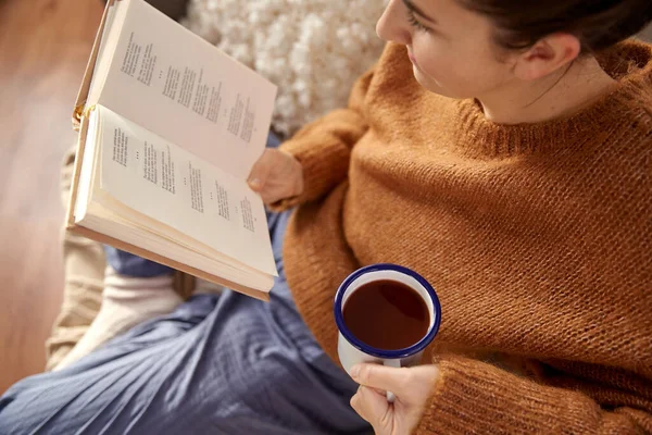 Vrouw die boek leest en thuis koffie drinkt — Stockfoto