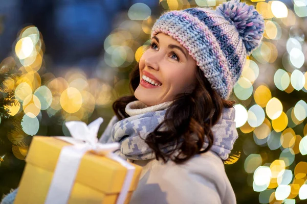 Işıkların üzerinde Noel hediyesi taşıyan mutlu kadın. — Stok fotoğraf