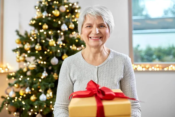 집에서 크리스마스 선물을 들고 할머니 미소짓고 있는 모습 — 스톡 사진
