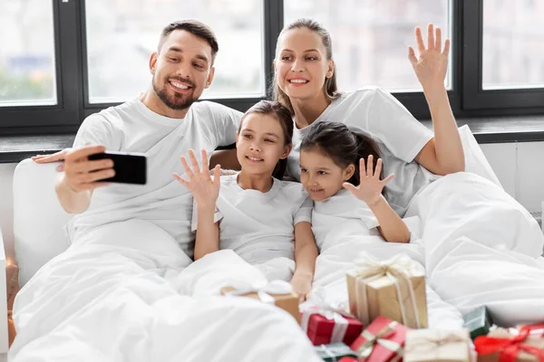 Familie met kerst geschenken nemen selfie in bed — Stockfoto