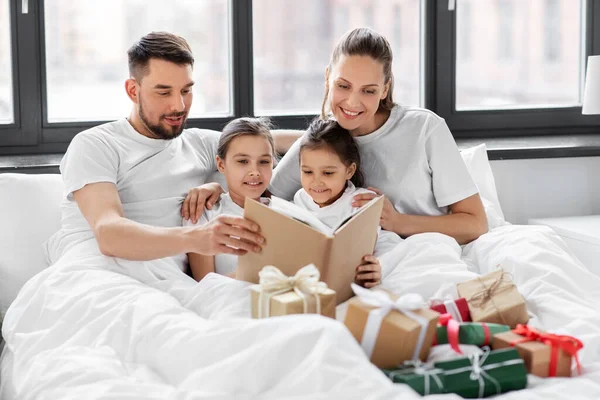 Mutlu aile kitapları Noel 'de yatakta okunur. — Stok fotoğraf