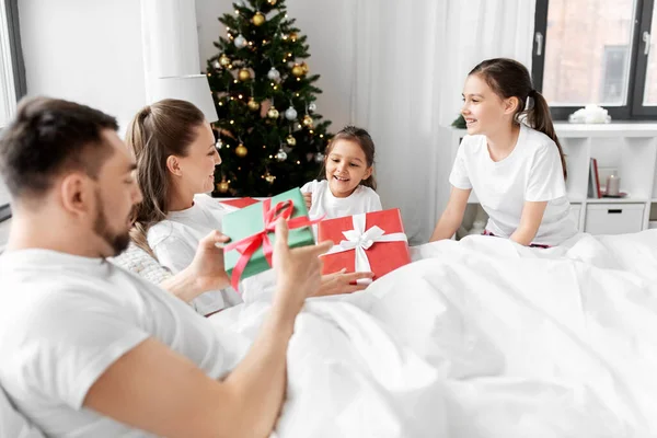 Familia feliz con regalos de Navidad en la cama en casa — Foto de Stock