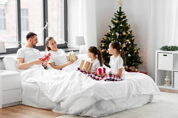Happy family with christmas gifts in bed at home Stock Photo