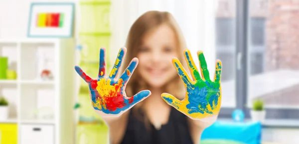 Usmívající se dívka ukazuje namalované ruce doma — Stock fotografie