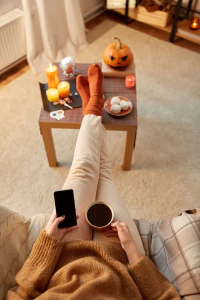 Жінка використовує смартфон вдома на Хеллоуїн — стокове фото