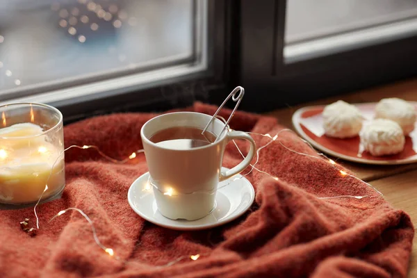 Cup of tea and candle on window sill — Stock Photo, Image