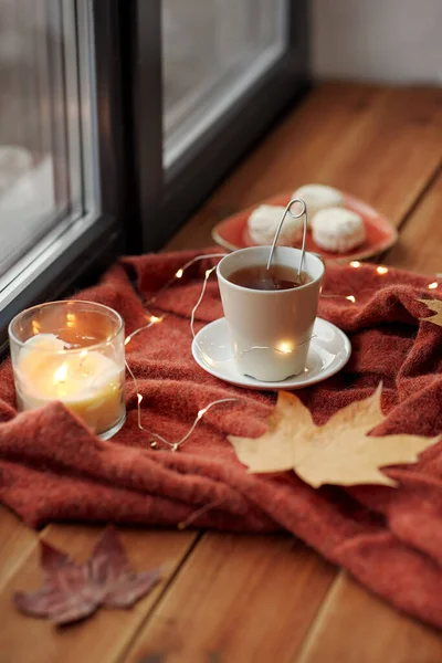 Xícara de chá e vela no peitoril da janela no outono — Fotografia de Stock