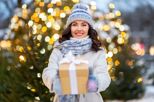 Glückliche Frau mit Weihnachtsgeschenk über Lichtern — Stockfoto