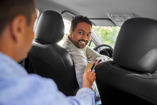 Taxichaufför som tar kreditkort från passagerare — Stockfoto