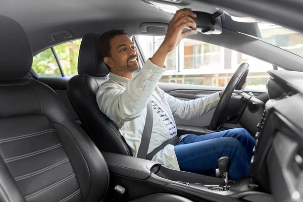 Boldog indiai férfi vagy járművezető beállító tükör az autóban — Stock Fotó