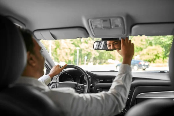 Homem indiano feliz ou motorista ajustando espelho no carro — Fotografia de Stock