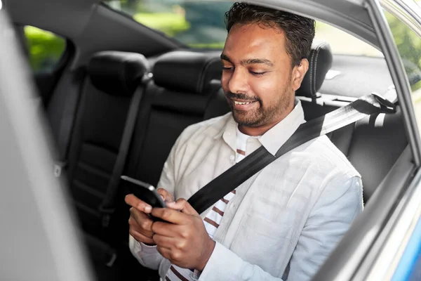 Homme indien souriant avec smartphone en voiture de taxi — Photo