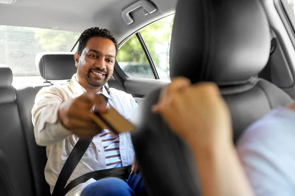 Indiana homem dando cartão de crédito para táxi motorista de carro — Fotografia de Stock