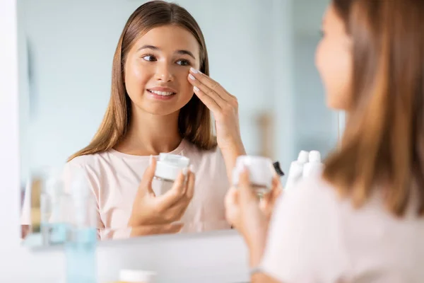 Teenage girl with moisturizer at bathroom — Stock Photo, Image