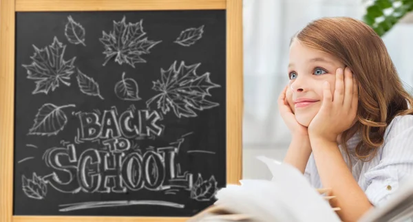 Student flicka med böcker över skolan tavlan — Stockfoto