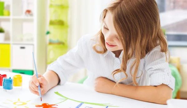 Ragazza felice con pennello e colori disegno a casa — Foto Stock