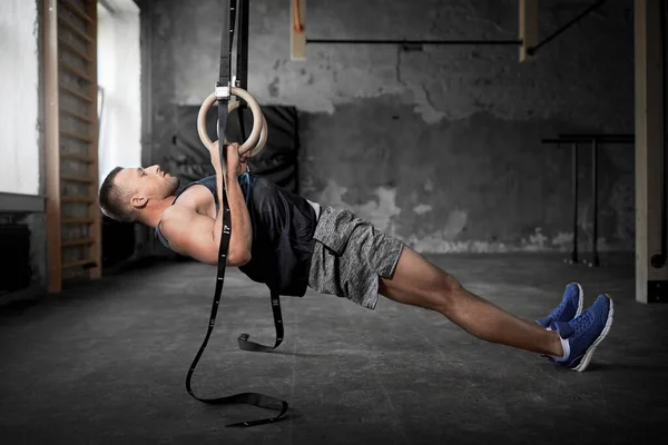 Homme faisant de l'exercice sur les anneaux de gymnastique dans la salle de gym — Photo