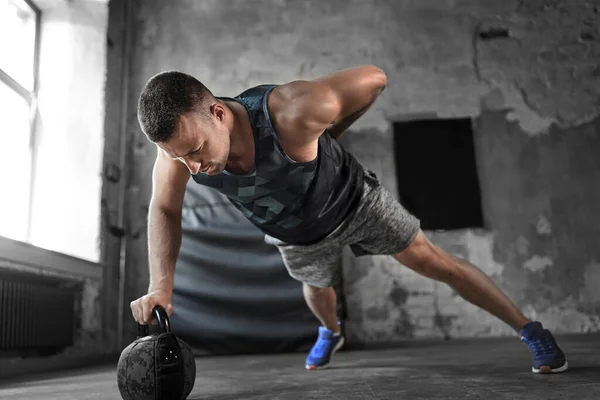 Joven haciendo flexiones kettlebell en el gimnasio — Foto de Stock