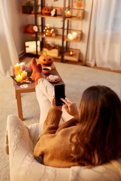 Cadılar bayramında evde akıllı telefon kullanan bir kadın. — Stok fotoğraf