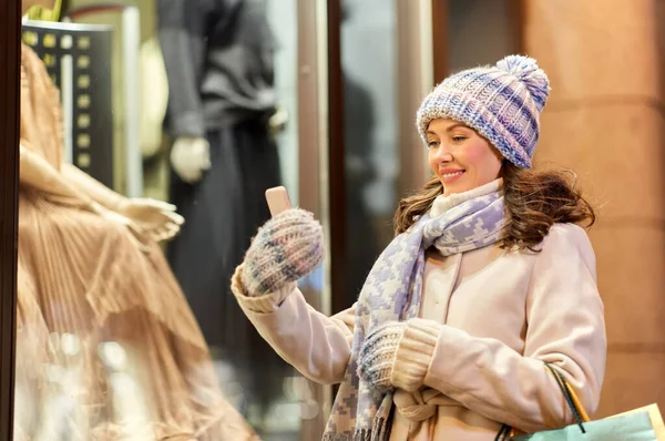 Woman with shopping bags and smartphone in winter — Stock Photo, Image