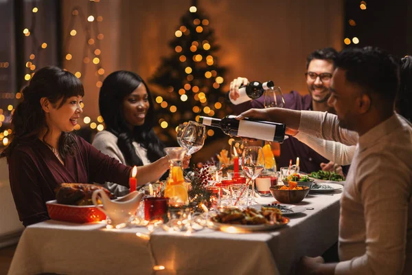 Счастливые друзья пьют вино на рождественской вечеринке — стоковое фото