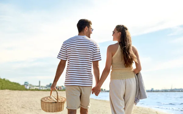 Lyckligt par med picknickkorg promenader på stranden — Stockfoto