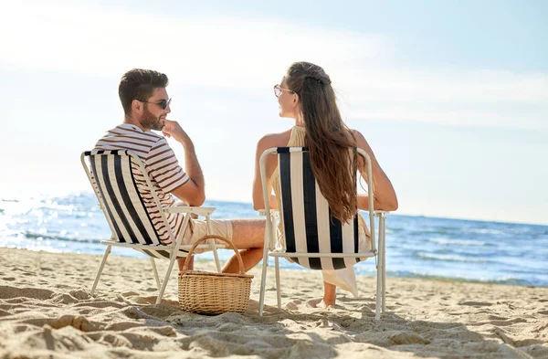 Felice coppia seduta in sedie pieghevoli sulla spiaggia — Foto Stock