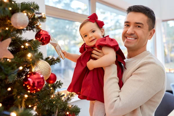 Mutlu baba ve kız bebek Noel ağacını süslüyor. — Stok fotoğraf