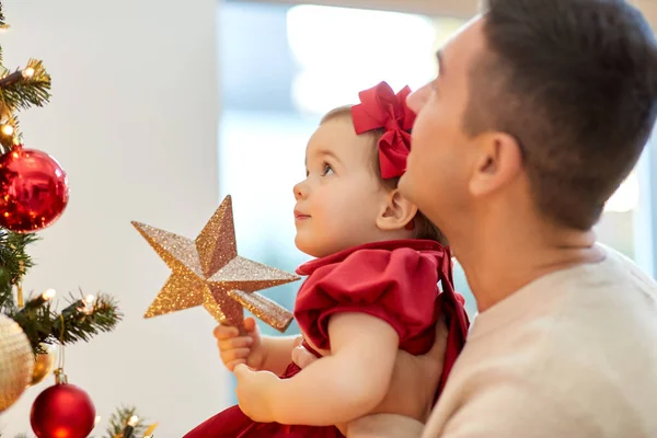 幸せな父親と赤ちゃんの女の子はクリスマスツリーを飾る — ストック写真