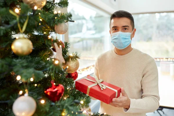 Hombre enmascarado con regalo en el árbol de Navidad en casa —  Fotos de Stock